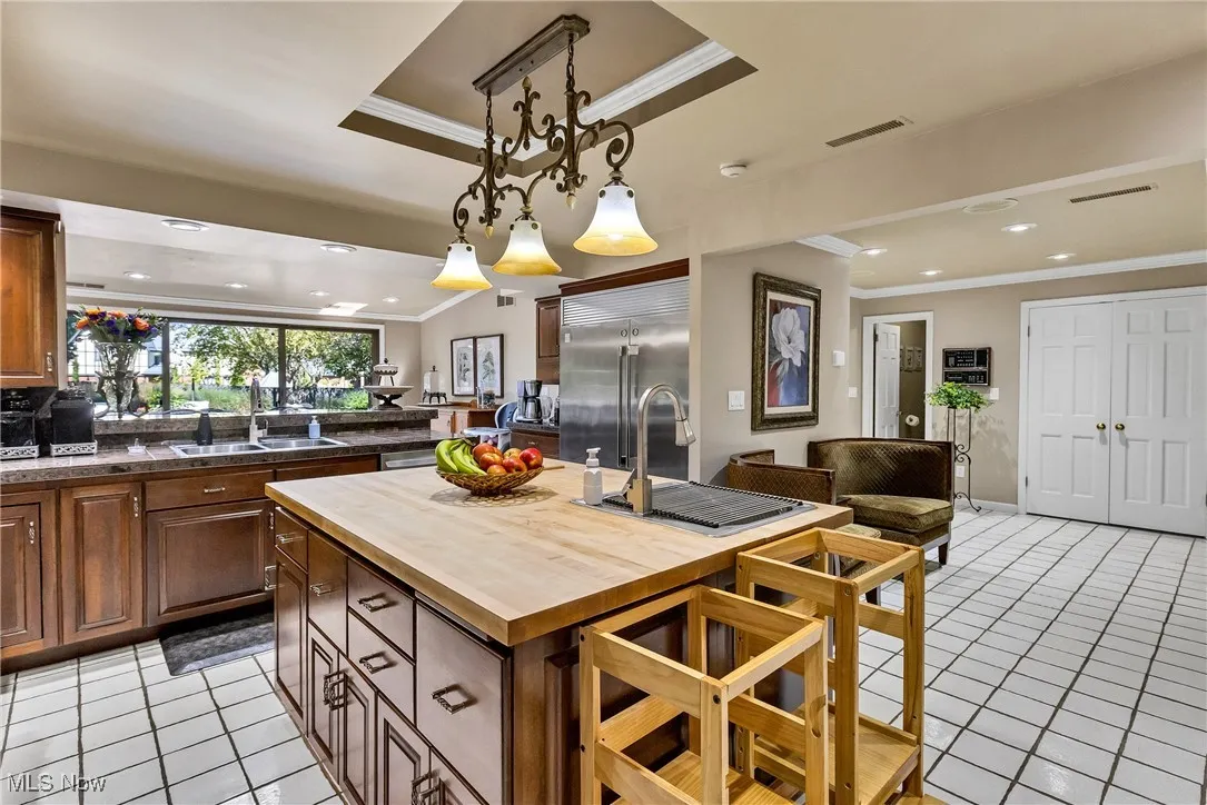 Kitchen featuring ornamental molding, wood counters, light tile patterned flooring, recessed lighting, and built in refrigerator