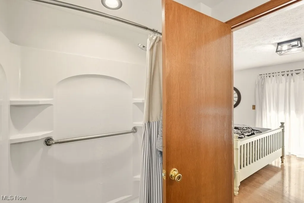 Bathroom featuring a shower with shower curtain, wood finished floors, and a textured ceiling