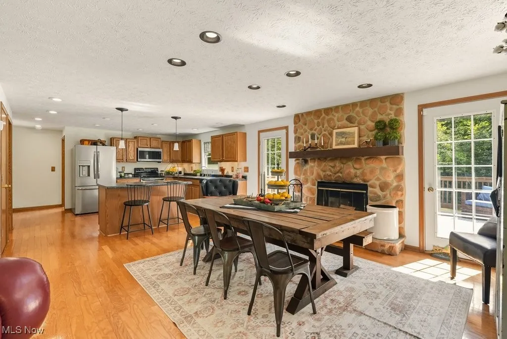 Dining area featuring a fireplace, light wood-style flooring, a textured ceiling, and recessed lighting