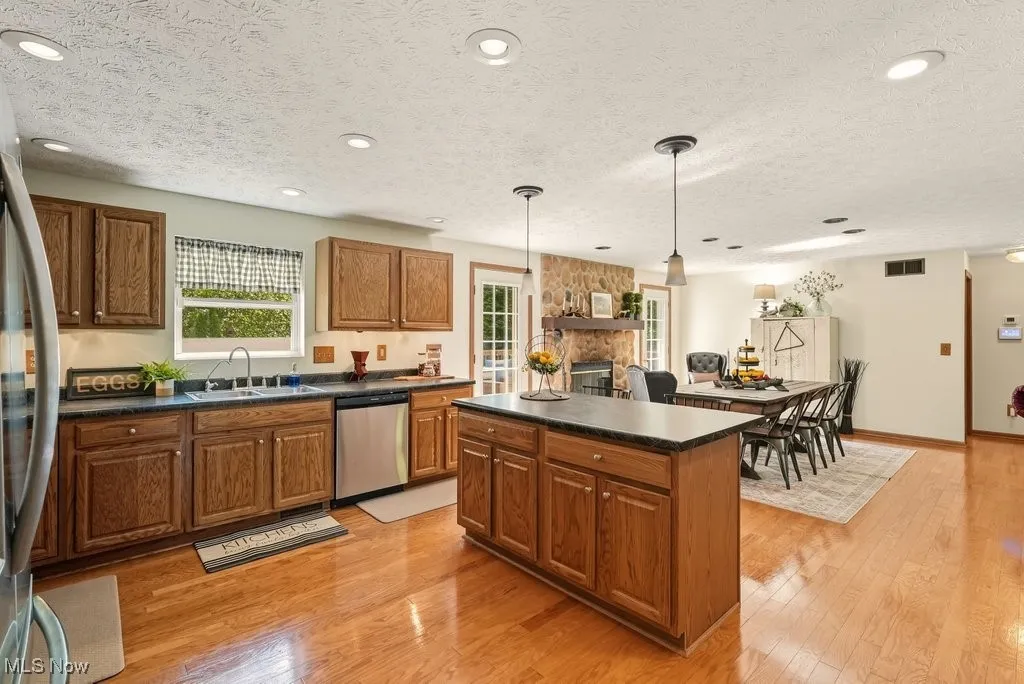 Kitchen featuring light wood-style floors, dark countertops, brown cabinets, pendant lighting, and a textured ceiling