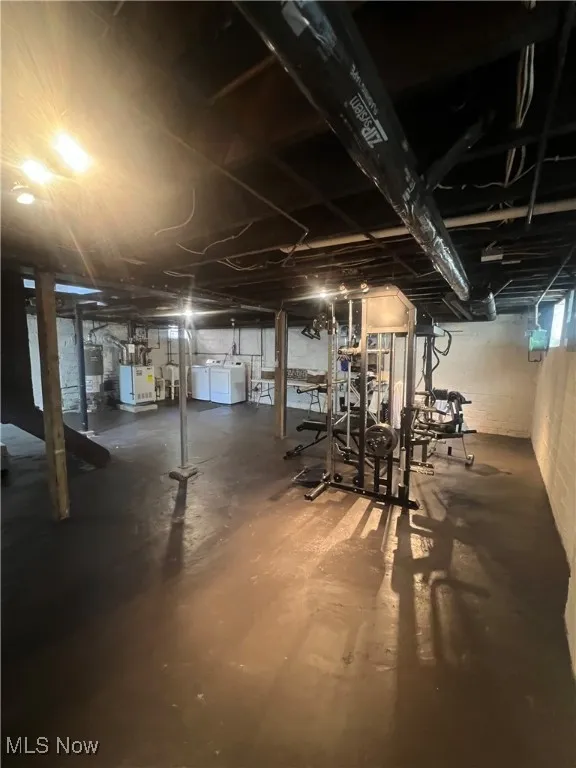 Unfinished below grade area featuring water heater, a heating unit, and washer and dryer