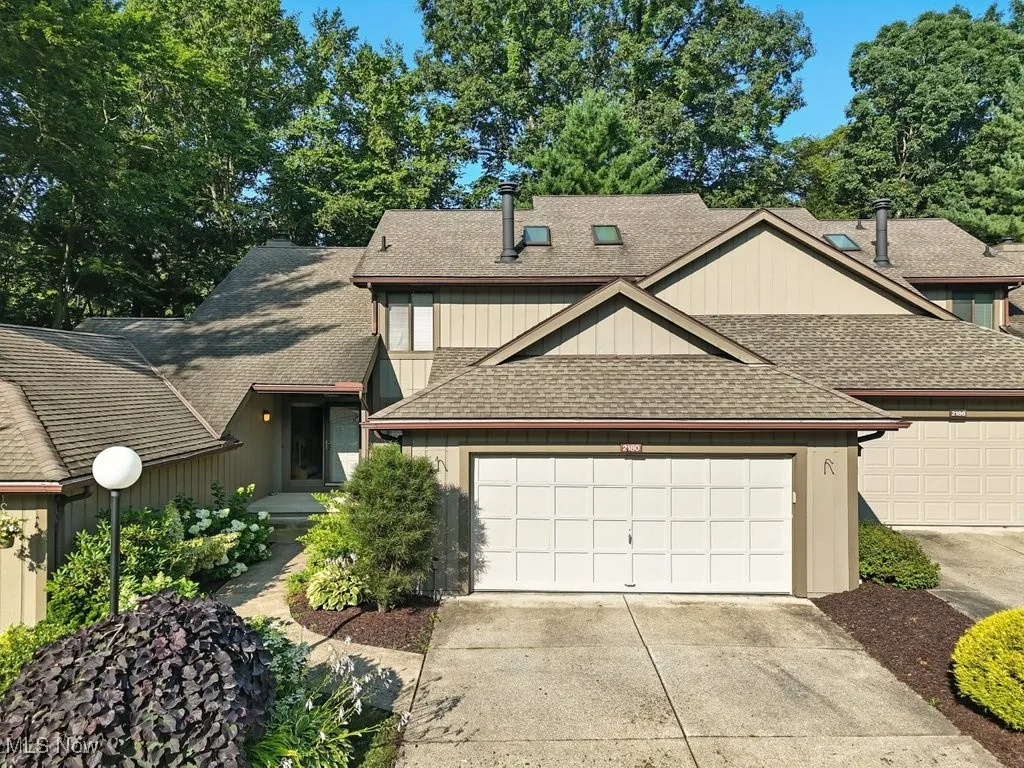 View of front of home with a shingled roof, driveway, and a garage