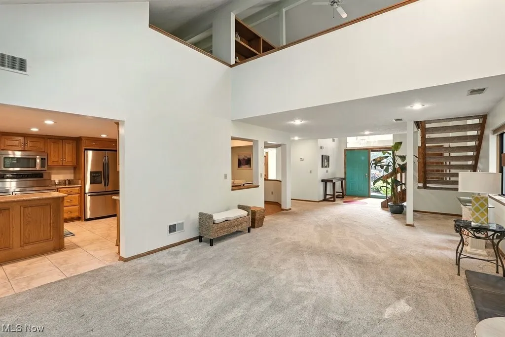 Living room featuring light carpet, a towering ceiling, and light tile patterned floors