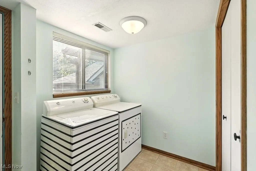 Laundry area featuring light tile patterned flooring, independent washer and dryer, and a textured ceiling