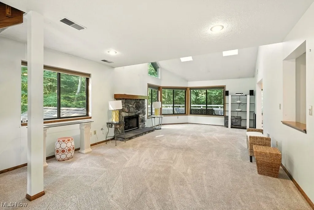 Unfurnished living room featuring carpet floors, vaulted ceiling, a fireplace, and a textured ceiling