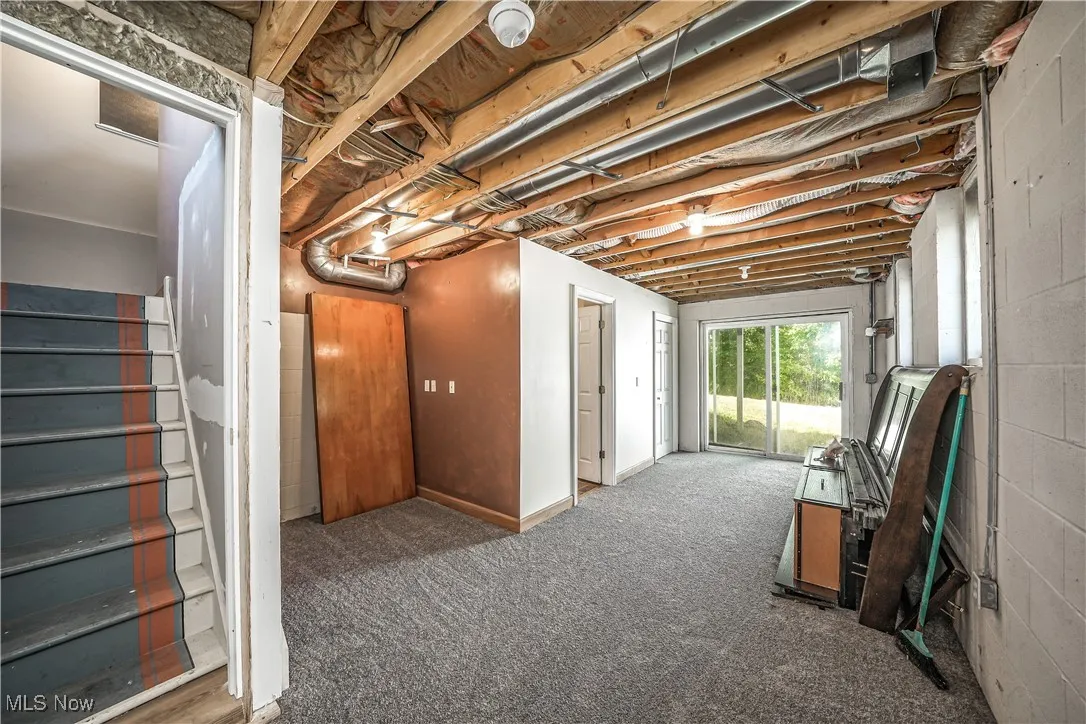 Below grade area with stairs, carpet, and concrete block wall