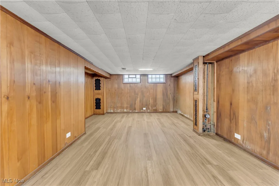Below grade area featuring light wood-style flooring and wood walls