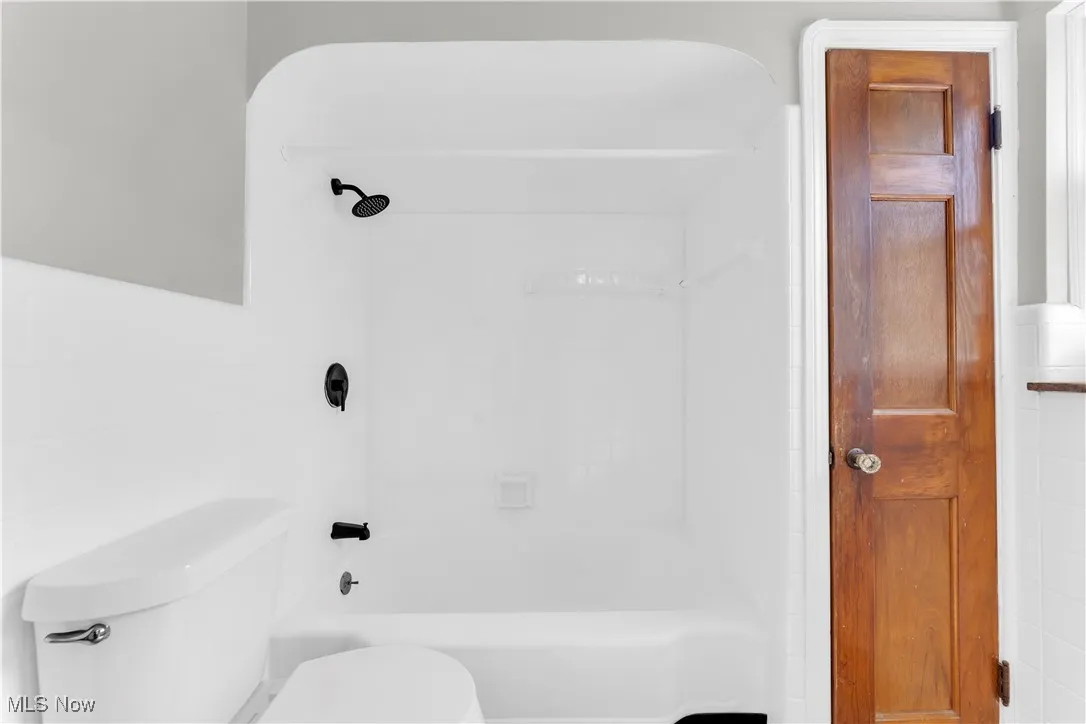 Bathroom with washtub / shower combination and tile walls