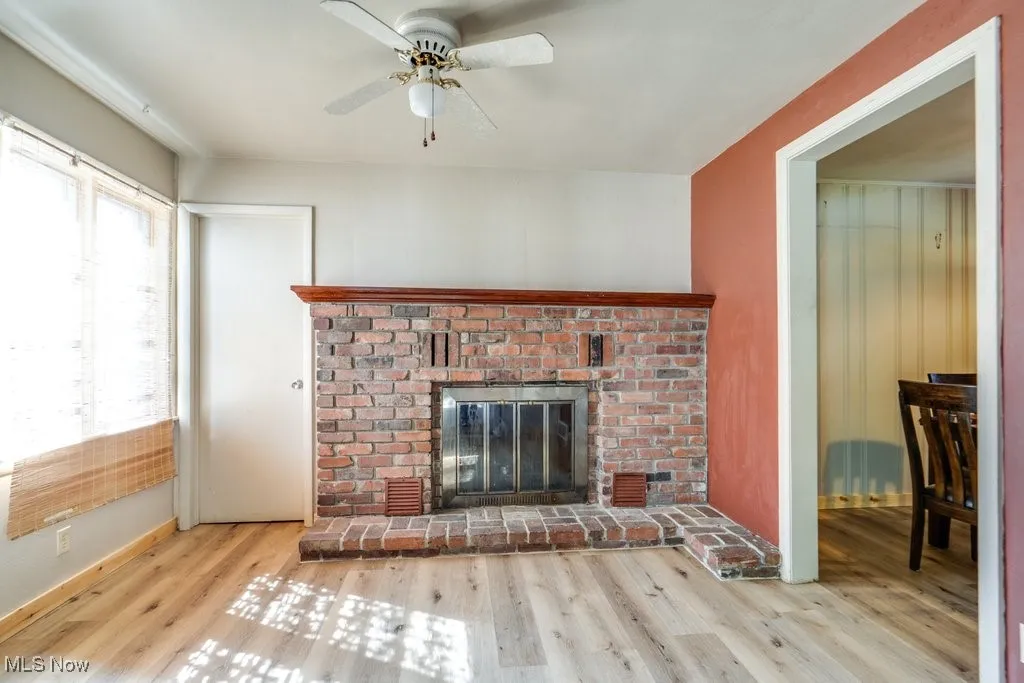 Unfurnished living room featuring a fireplace, wood finished floors, and a ceiling fan
