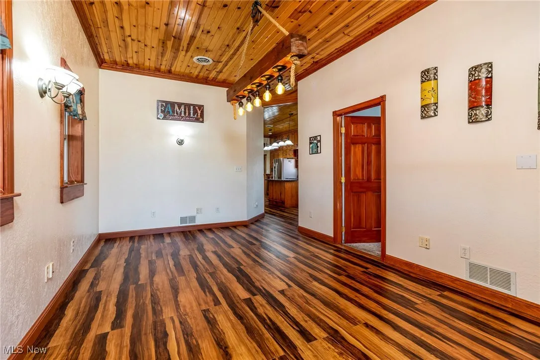 Unfurnished room with dark wood-type flooring, wood ceiling, and ornamental​​‌​​​​‌​​‌‌​‌‌​​​‌‌​‌​‌​‌​​​‌​​ molding