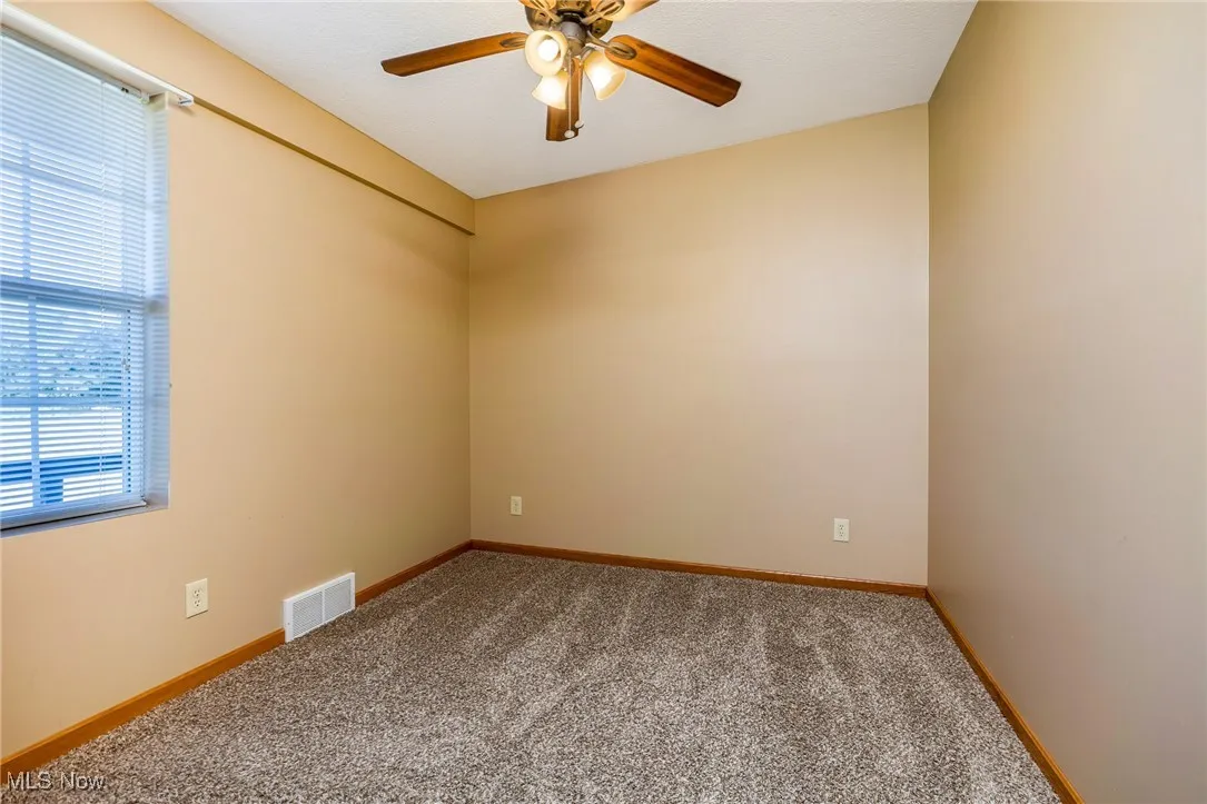 Carpeted spare room with baseboards and a ceiling fan