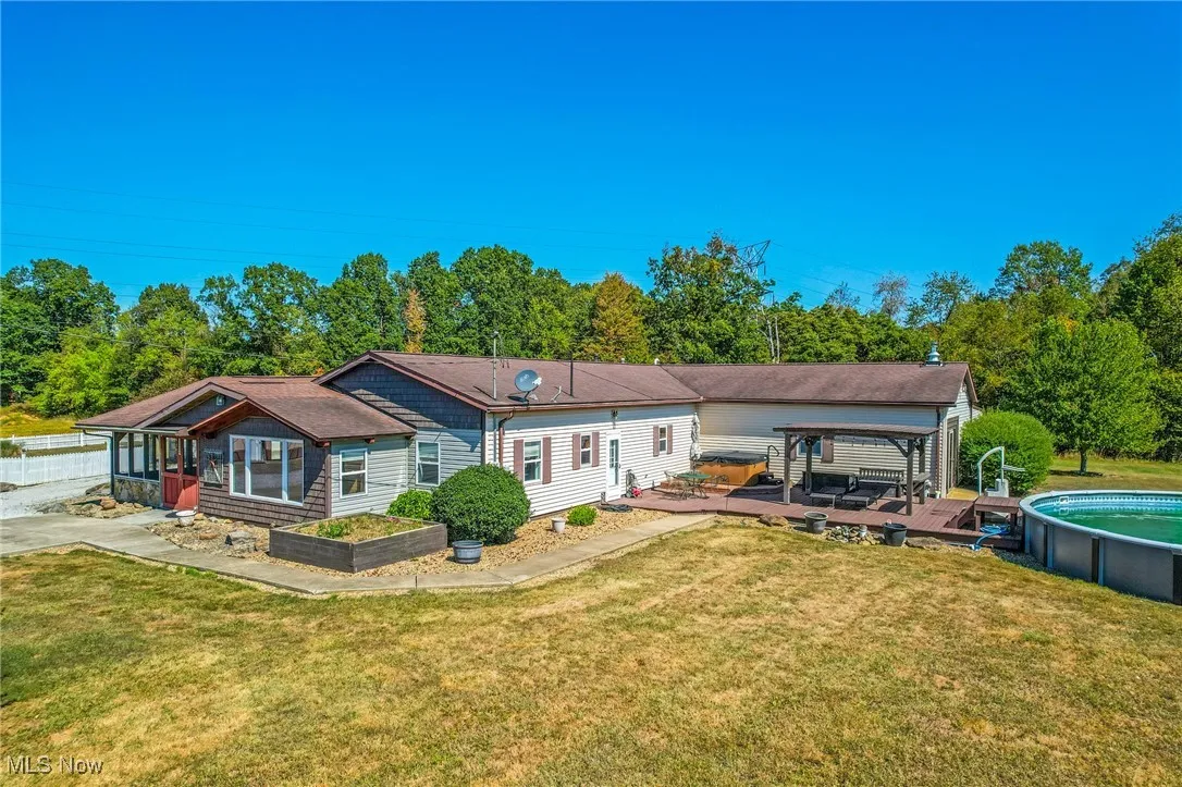 Rear view of house with a lawn, an outdoor pool, and view of wooded area
