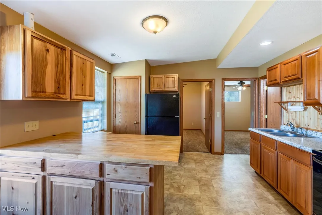 Kitchen with black appliances, a peninsula, brown cabinetry, a ceiling fan, and recessed lighting