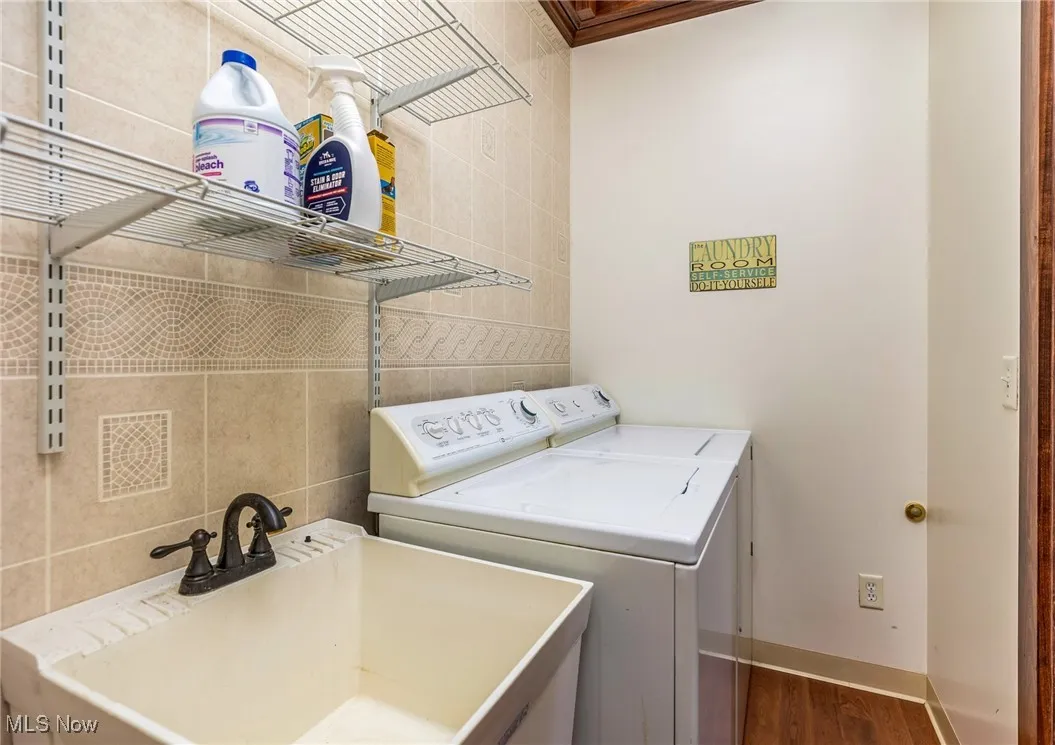 Laundry area with tile walls, dark wood-style floors, and washer and clothes dryer