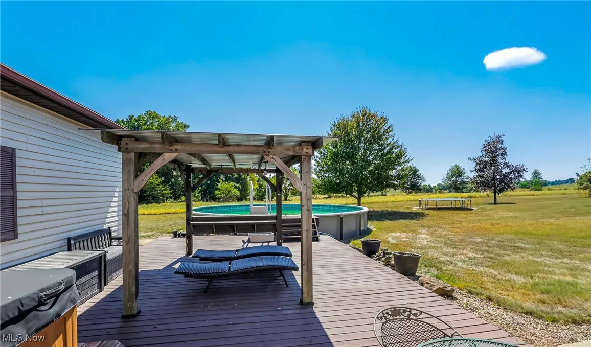 Wooden terrace featuring a lawn and an outdoor pool