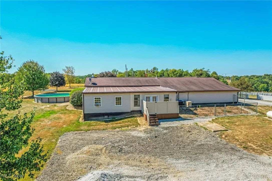 View of front of home with an outdoor pool and a metal roof
