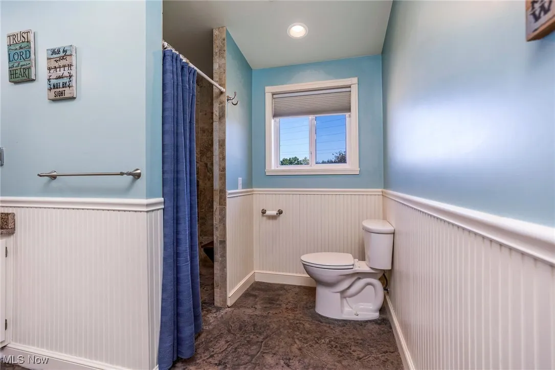 Bathroom featuring wainscoting and a shower with curtain