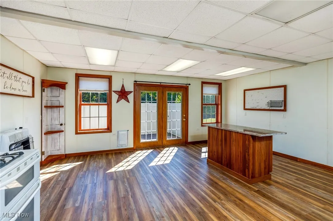 Unfurnished office with dark wood-style floors, a paneled ceiling, and heating unit
