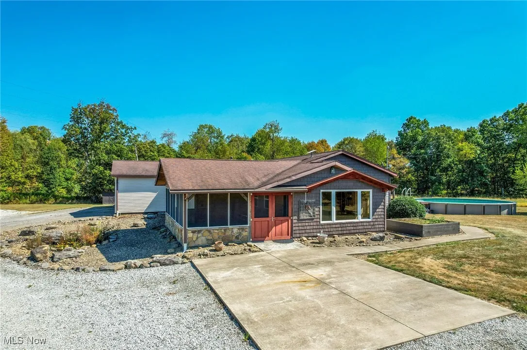 View of front of home with a sunroom and an outdoor pool