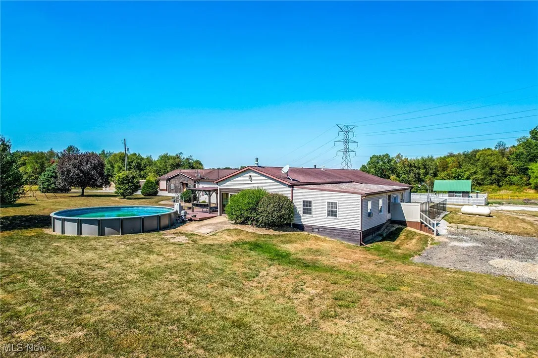 Rear view of house featuring an outdoor pool, a lawn, and a patio area
