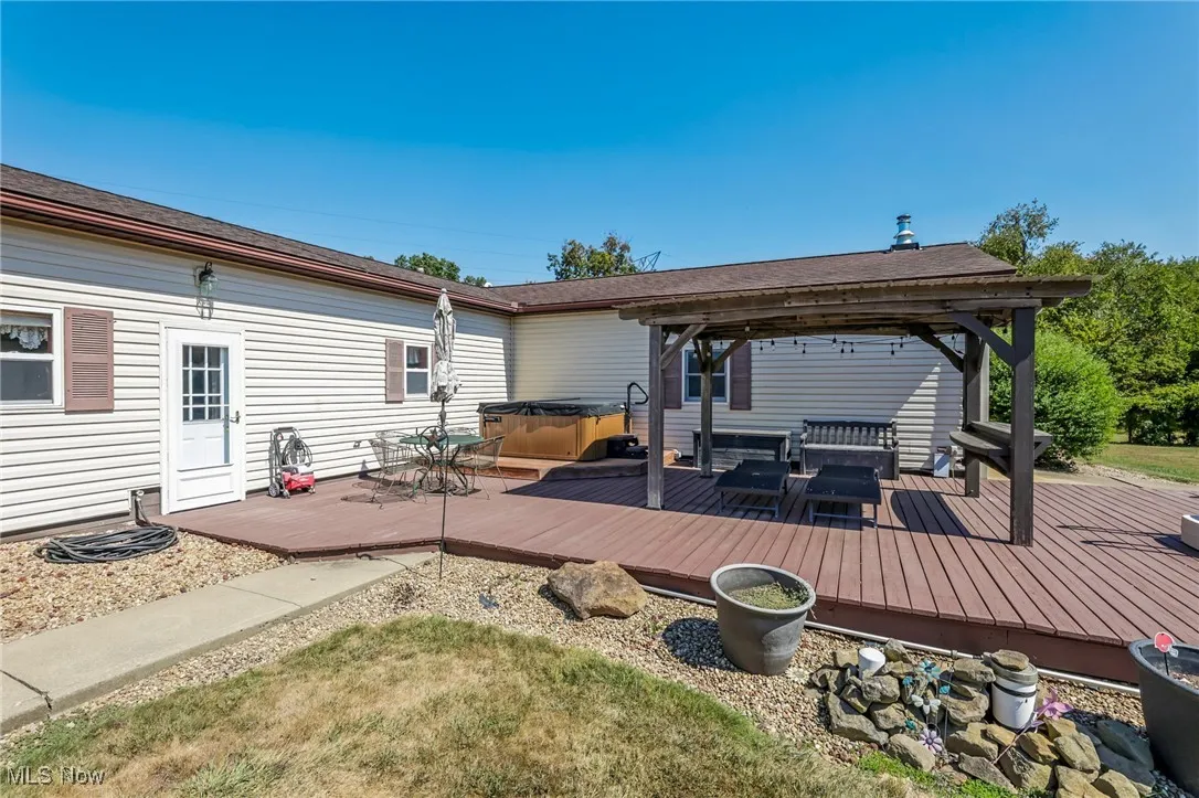 Wooden terrace featuring a hot tub, a gazebo, and a grill
