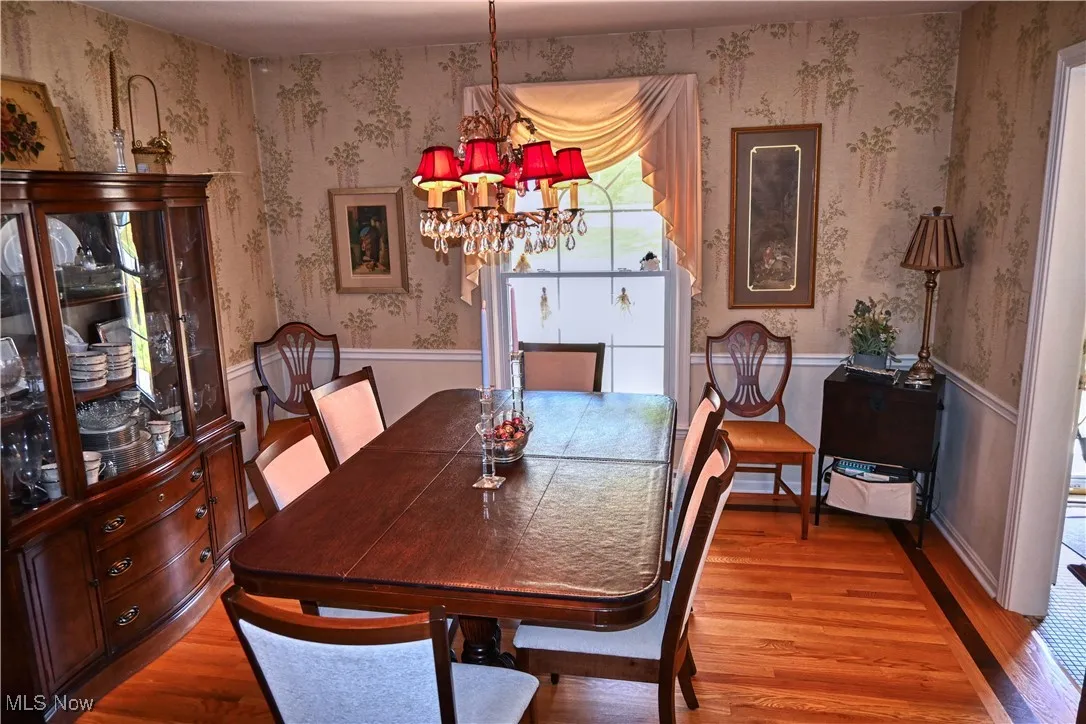 Dining area featuring wood finished floors, a chandelier, and wainscoting
