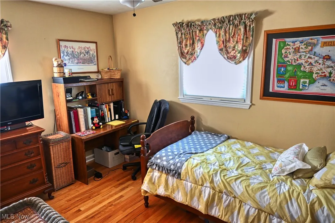 Bedroom with wood finished floors and an office area