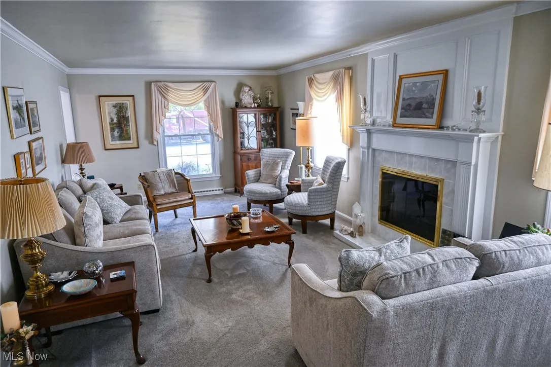Carpeted living room with a tiled fireplace and crown molding