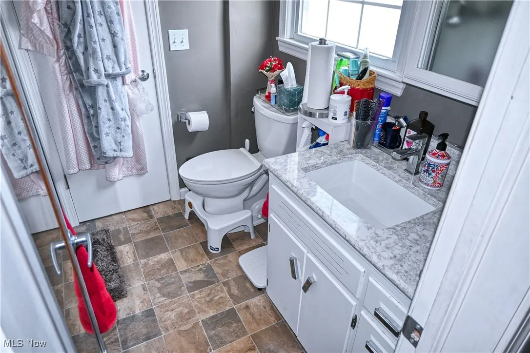 Half bath featuring stone finish floors and vanity