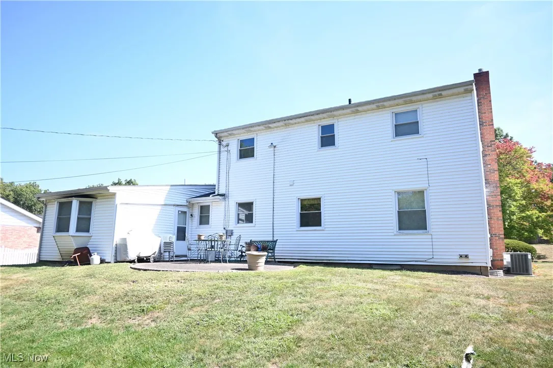 Rear view of house with a patio, a yard, and a chimney