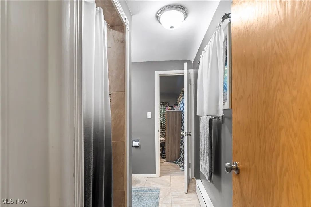 Hallway featuring light tile patterned flooring and a baseboard radiator