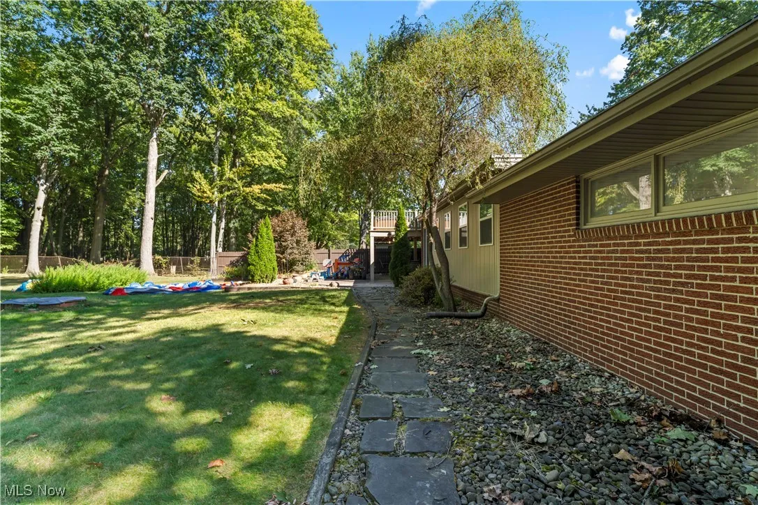 View of grassy yard with view of wooded area
