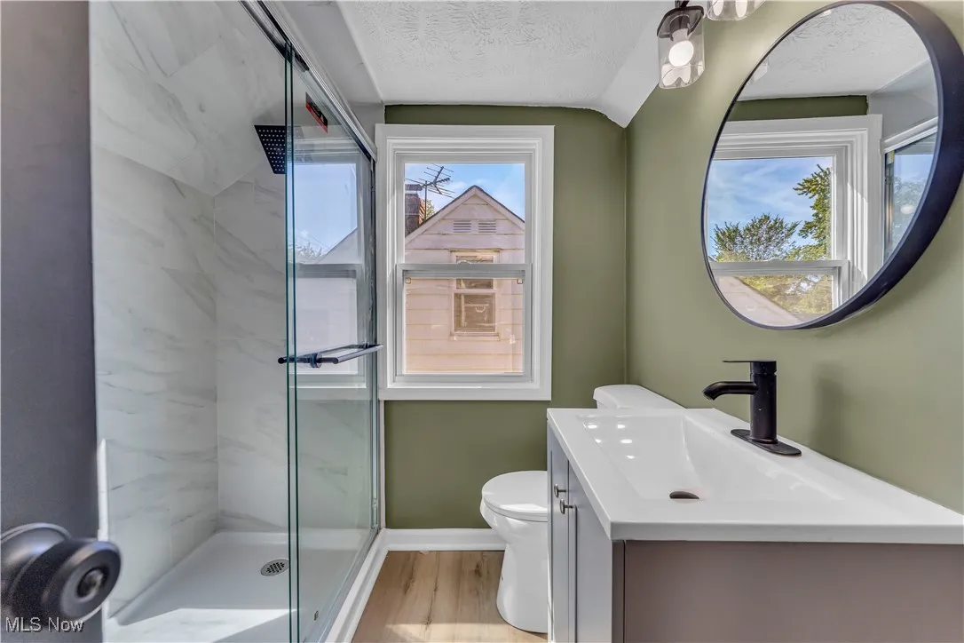 Full bathroom with vanity, a marble finish shower, light wood finished floors, and a textured ceiling