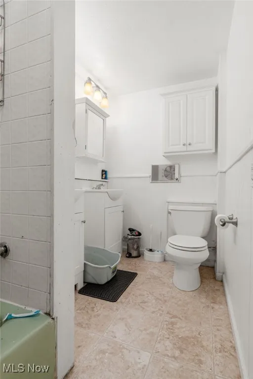 Bathroom featuring vanity, wainscoting, and light tile patterned flooring