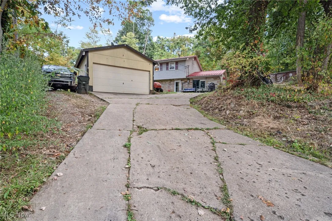 Tri-level home featuring an outdoor structure, a garage, concrete driveway, and a metal roof