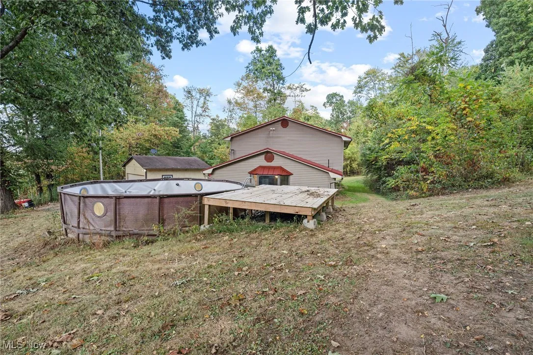 View of green lawn featuring a wooden deck and an outdoor pool