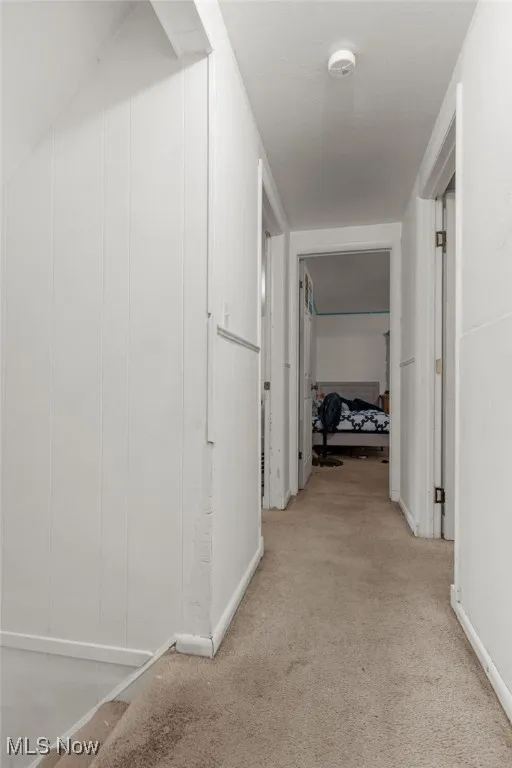 Hall featuring light colored carpet and baseboards