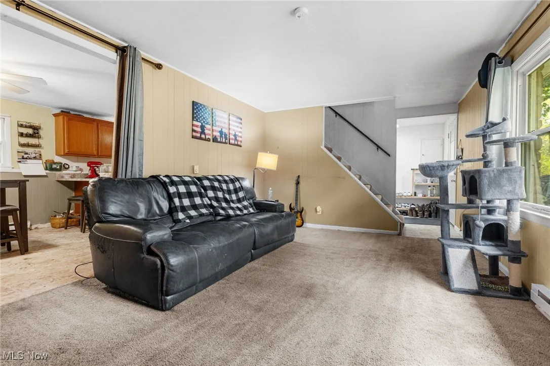 Living room featuring wood walls, light colored carpet, and stairs