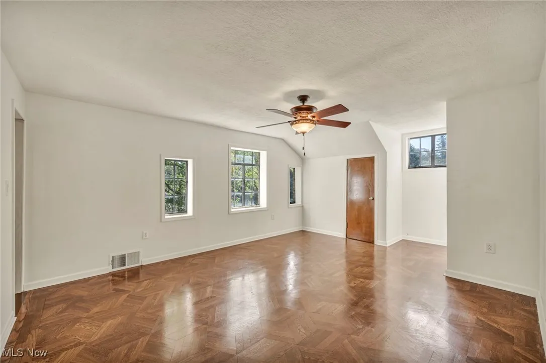 Empty room with healthy amount of natural light, a textured ceiling, and a ceiling fan