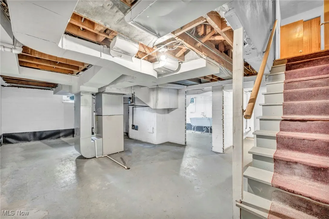 Unfinished basement featuring stairs and heating unit