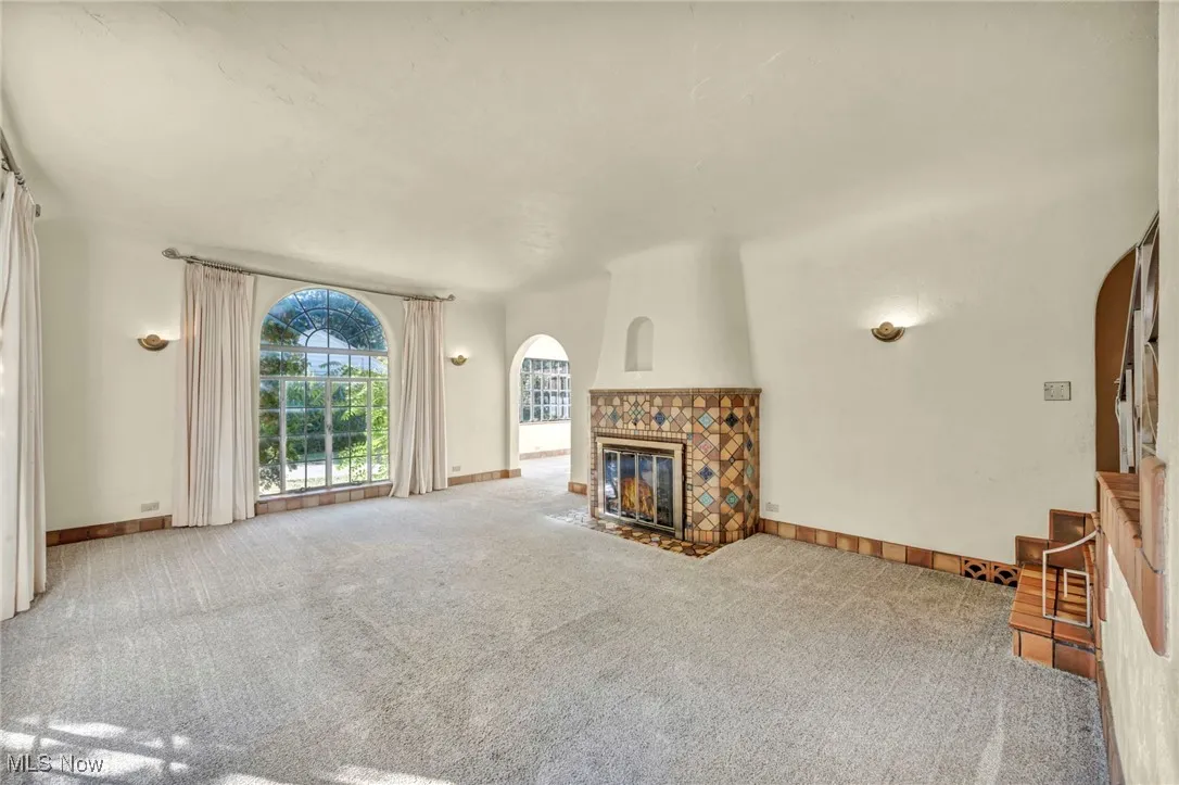 Unfurnished living room with a tiled fireplace and carpet flooring