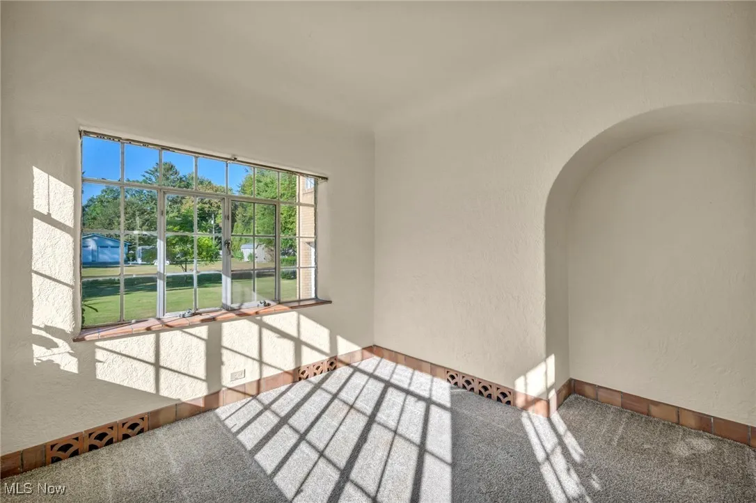 Spare room featuring a textured wall, arched walkways, and carpet floors