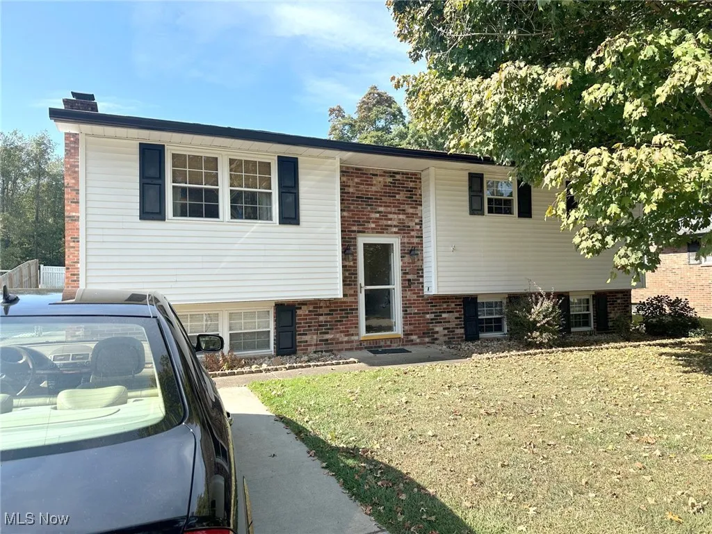 Bi-level home featuring brick siding, a front yard, and a chimney