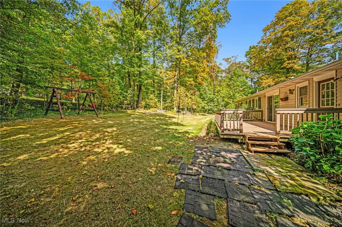 View of green lawn with a wooden deck and a playground