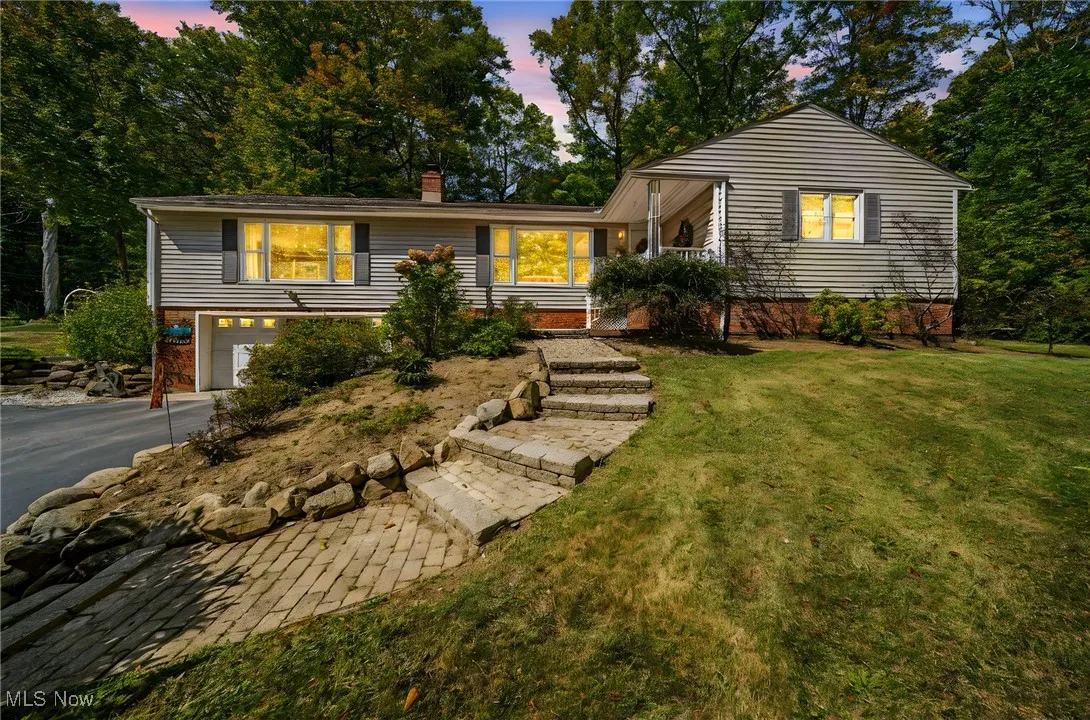 Ranch-style house featuring a garage, a chimney, asphalt driveway, and a front yard