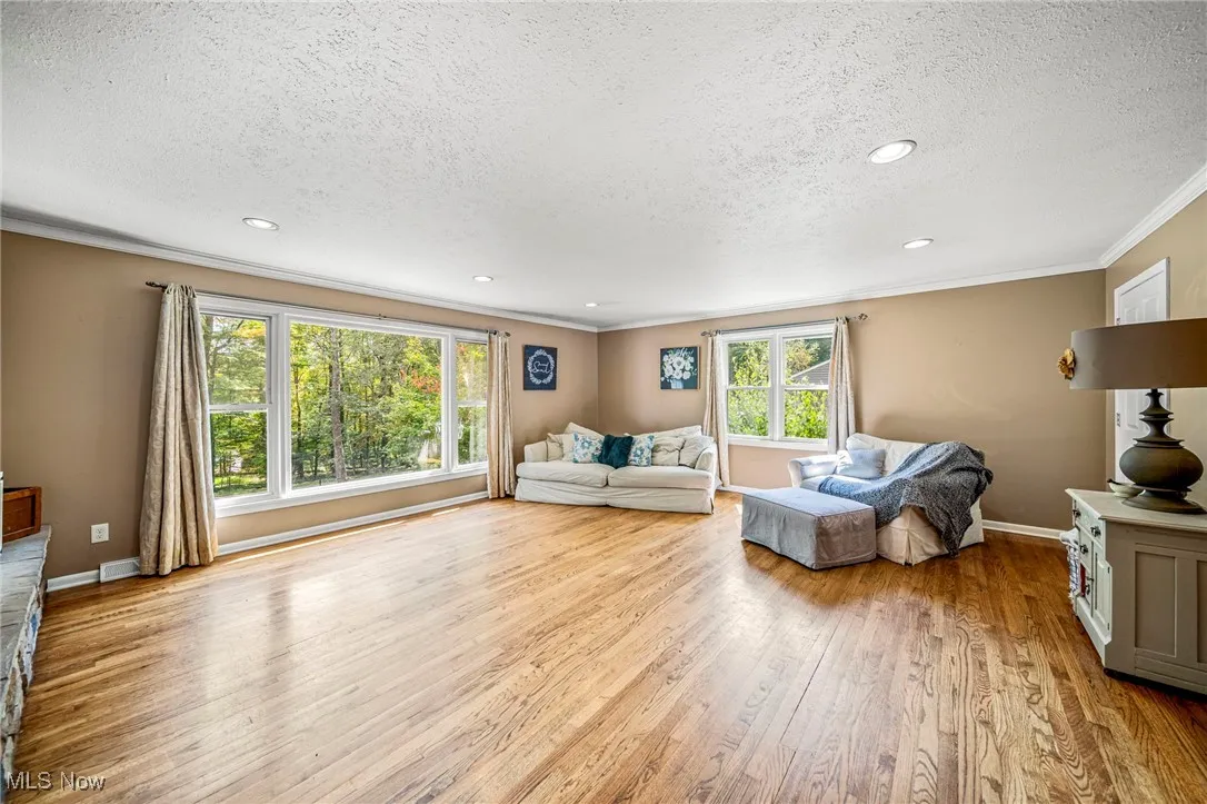 Living area with ornamental molding, light wood finished floors, and recessed lighting