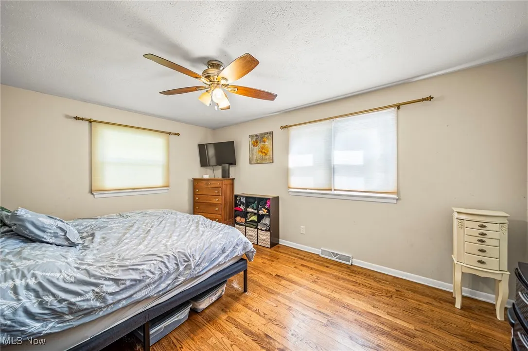 Bedroom featuring a textured ceiling, hardwood / wood-style flooring, and ceiling fan