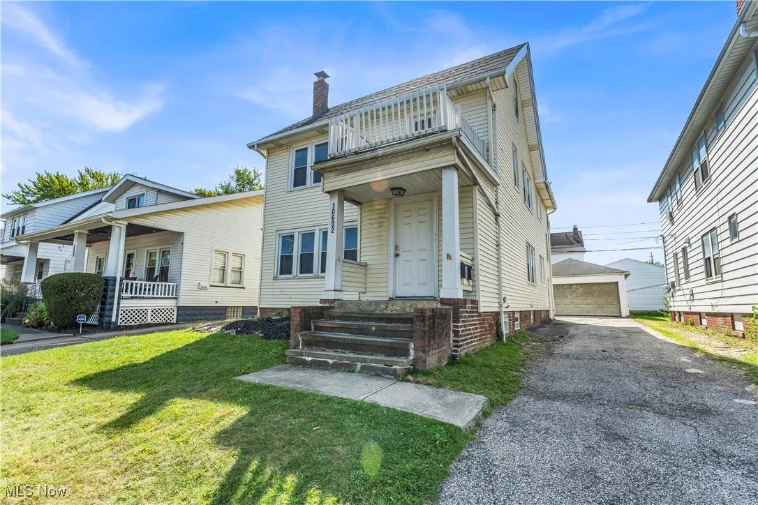 View of front of home featuring an outbuilding, a front lawn, a chimney, and a garage