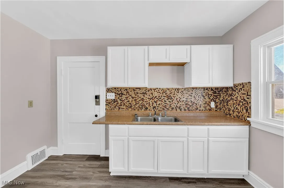Kitchen featuring white cabinetry, dark wood finished floors, decorative backsplash, and light countertops