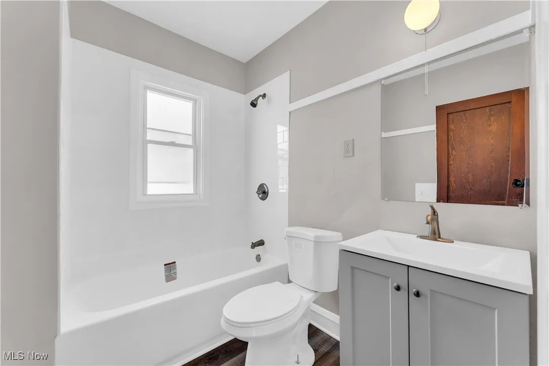 Full bathroom featuring shower / washtub combination, vanity, and dark wood-type flooring
